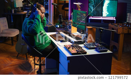 Artist composer recording a new track on his home studio microphone, editing his song with professional gear. Adjusting volume levels and adding sound effects, mix and master. Camera B. 121799572