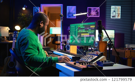 Audio technician works with recording tools in his home studio, using mixing console and pre amp knobs to add sound effects on tracks. Composer editing new tunes in post production. Camera B. 121799579