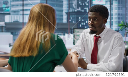 New employee signing his work contract after successful job interview with the HR staff, businesswomen shaking hands and welcoming man to the team. Job applicant securing a position. Camera A. 121799591