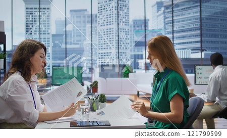 HR staff consulting each other in choosing the right candidate for the job opening, looking for talented people. Recruiters evaluating the resumes of the applicants after the interview. Camera B. HR staff consulting each other in choosing the right candidate for the job opening, looking for talented people. Recruiters evaluating the resumes of the applicants after the interview. Camera B. 121799599