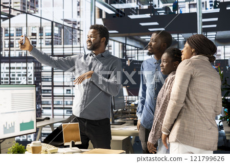 African american business workers smiling at pictures in the office, taking a break from administrative tasks and enjoying photos. Black employees friendly staff work in an enterprise. 121799626