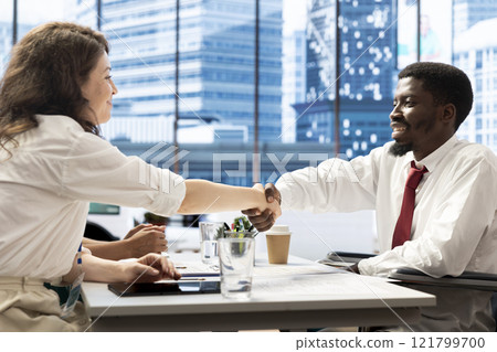 HR expert doing handshake with person with disability, vetting applicants to ensure skills match role needs. Headhunter talking with man in wheelchair, shaking hands after assessing work experience 121799700
