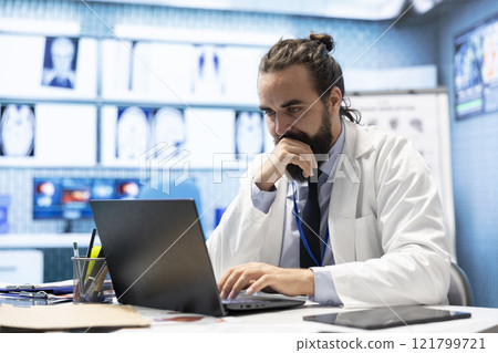 General practitioner working with hospital records and test results to find the diagnosis in his cabinet, examining x rays and reports. Doctor doing research for disease prevention and treatment. General practitioner working with hospital records and test results to find the diagnosis in his cabinet, examining x rays and reports. Doctor doing research for disease prevention and treatment. 121799721