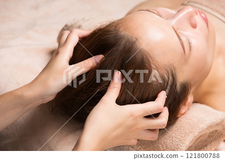 一位年輕的亞洲女性正在接受頭部按摩。 一位年輕的亞洲女性正在接受頭部按摩。 121800788