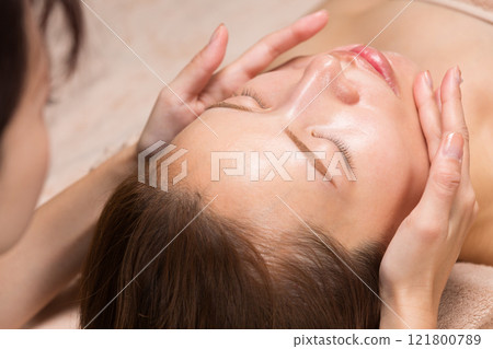 年輕的亞洲女性正在接受臉部按摩。 121800789