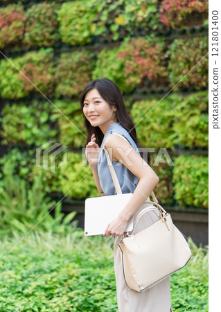 女商人在綠牆建築前拿著平板電腦 121801400