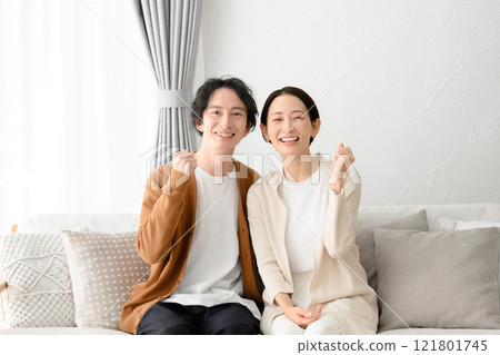 Man and woman sitting on sofa in living room 121801745