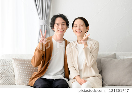 Man and woman sitting on sofa in living room 121801747
