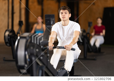 Man exercising on a rowing machine 121802706