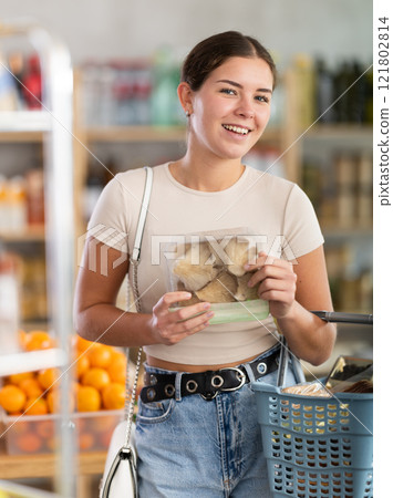 Young woman holding plastic containers with oyster mushrooms, choose mushrooms. 121802814