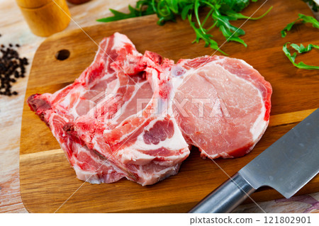 Uncooked pork loin steaks with black pepper and greenery 121802901