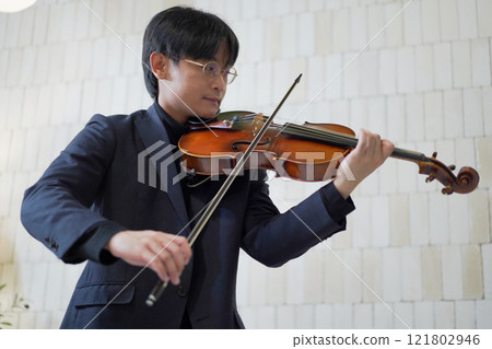 Solo classical musician is playing viola. A solo Asian young professional musician is playing or practicing a viola alone at home. Skillful classical musician plays a viola or violin. Solo classical musician is playing viola. A solo Asian young professional musician is playing or practicing a viola alone at home. Skillful classical musician plays a viola or violin. 121802946