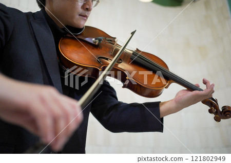 Solo classical musician is playing viola. A solo Asian young professional musician is playing or practicing a viola alone at home. Skillful classical musician plays a viola or violin. Solo classical musician is playing viola. A solo Asian young professional musician is playing or practicing a viola alone at home. Skillful classical musician plays a viola or violin. 121802949