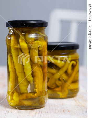 Pickled chilli peppers in a glass jar on wooden table Pickled chilli peppers in a glass jar on wooden table 121802953