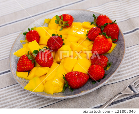 Mango pieces served with juicy strawberries 121803046
