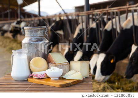 Fresh dairy products on table on background of cows in stall 121803055