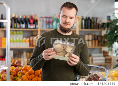 Man holds a package of oyster mushrooms in his hands 121803115