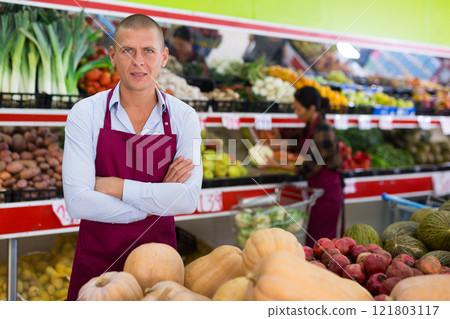 Man in apron standing in greengrocer Man in apron standing in greengrocer 121803117