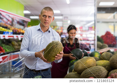 Man choosing melon in greengroce 121803124