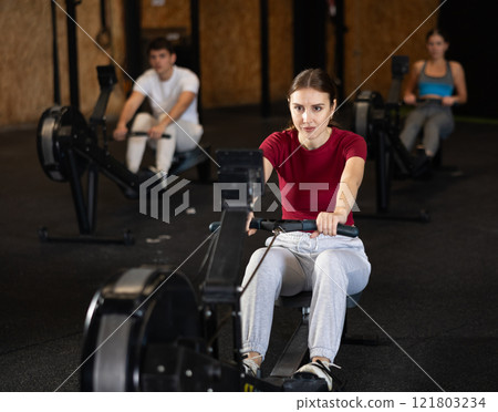 Woman exercising on a rowing machine 121803234