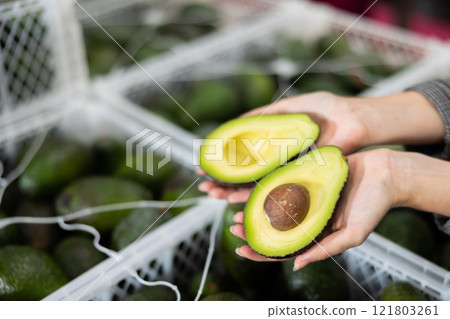 Halves of ripe avocado in hands of female ruit sorting factory worker 121803261
