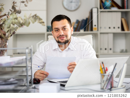 Positive man bookkeeper doing paperwork in office Positive man bookkeeper doing paperwork in office 121803262