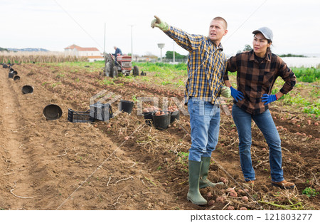 Man and woman farmers standing on potato field Man and woman farmers standing on potato field 121803277