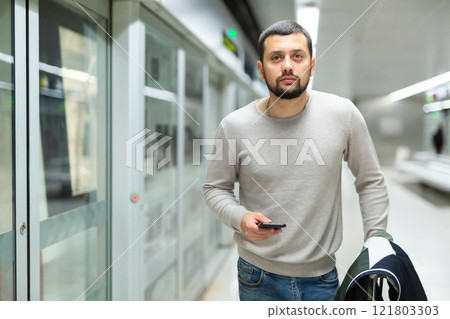 Young man browsing messages on phone at subway station 121803303