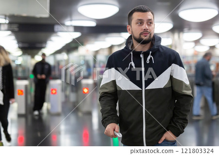 Man in jacket with a mobile phone near turnstile in subway 121803324