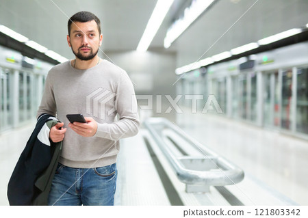 Portrait of confident man traveling on subway and using smartphone 121803342