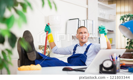 Relaxed cleaning service worker sitting in office with feet on table Relaxed cleaning service worker sitting in office with feet on table 121803344