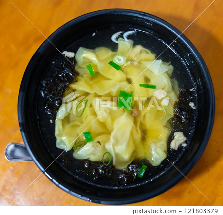 Wonton soup is cooked dumplings filled with meat or seafood. They are served in broth, usually enriched with onions and other ingredients. Chinese cuisine Wonton soup is cooked dumplings filled with meat or seafood. They are served in broth, usually enriched with onions and other ingredients. Chinese cuisine 121803379