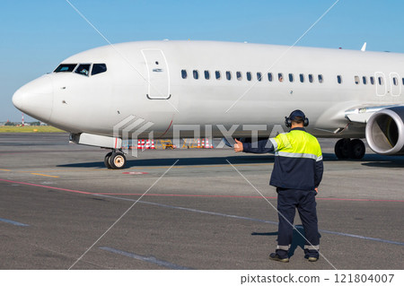 Aircraft marshaller showing take-off clearance sign to white passenger airplane 121804007