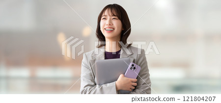 Smiling woman/businesswoman holding a computer and smartphone 121804207