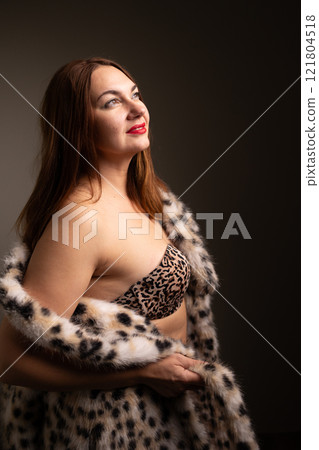 An elegant and seductive portrait of a woman dressed in a chic leopard-print fur coat 121804518