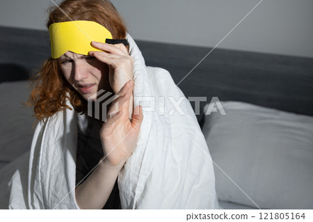 Young woman is struggling with sleep in her cozy, inviting bedroom, surrounded by comfort 121805164