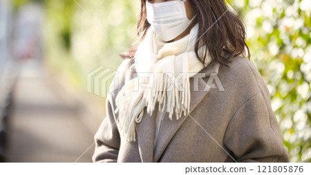 一名中年婦女穿著外套和口罩在鎮上行走 一名中年婦女穿著外套和口罩在鎮上行走 121805876