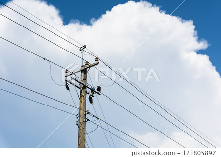 View of utility poles with blue sky and white clouds as a background. 121805897