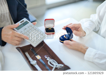 一位採購專家和一位中年婦女正在評估貴金屬 一位採購專家和一位中年婦女正在評估貴金屬 121805929