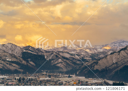 Snow-capped mountains and the townscape at the foot of the mountains bathed in the setting sun Snow-capped mountains and the townscape at the foot of the mountains bathed in the setting sun 121806171