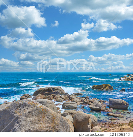 Rocks in the ocean under cloudy blue sky background with copy space. Beautiful landscape of beach waves splashing against boulders or stones in aqua sea water. Summer nature location in South Africa 121806343