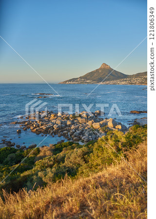 Landscape view of sea water, mountains and a blue sky with copy space of Lions Head in Cape Town, South Africa. Calm, serene and tranquil ocean and relaxing nature scenery with shrubs and brown grass 121806349