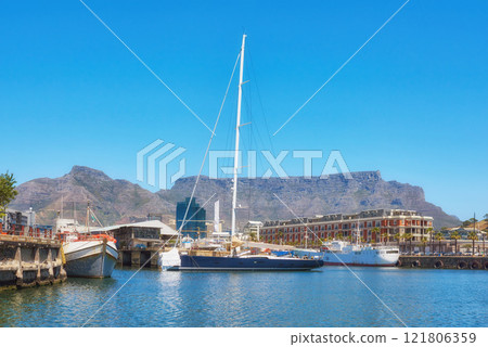 Sailboats docked at a harbor with Table Mountain in the background against blue sky with copy space. Scenic landscape of waterfront port at a marina dockyard. Nautical vessels for travel and tourism Sailboats docked at a harbor with Table Mountain in the background against blue sky with copy space. Scenic landscape of waterfront port at a marina dockyard. Nautical vessels for travel and tourism 121806359