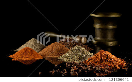Multi-colored heaps of spices and a bronze mortar on a black mirror background Multi-colored heaps of spices and a bronze mortar on a black mirror background 121806641
