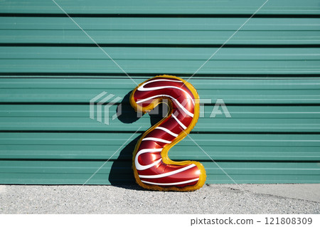 balloon in the shape of number 2 on a green wall 121808309