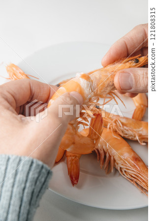 man removes the head of a cooked prawn man removes the head of a cooked prawn 121808315