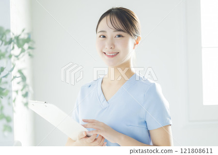 一名身穿白大褂的年輕女子，拿著病歷和活頁夾 121808611