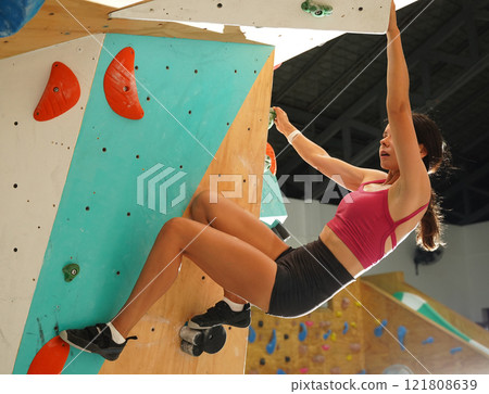 A strong female climber climbs an artificial wall with colorful grips 121808639