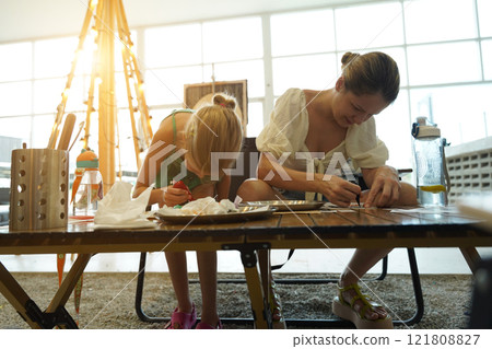 Mother and her daughter paint Halloween cookies  121808827