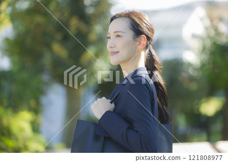 A woman in a suit walking down the sidewalk A woman in a suit walking down the sidewalk 121808977